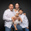 Happy family of four smiling at the camera in a Singapore portrait studio